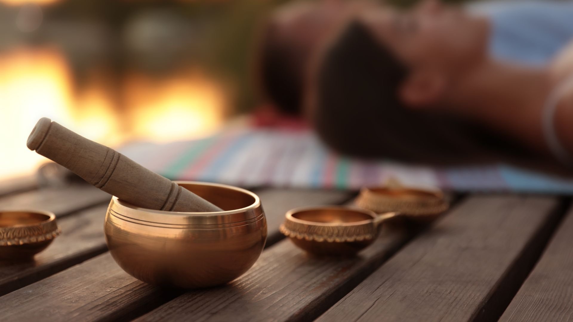 Bronze singing bowls with wooden mallet near warm fireplace